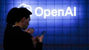 Silhouettes of people looking at smartphones in front of a blue tiled wall with the illuminated whit