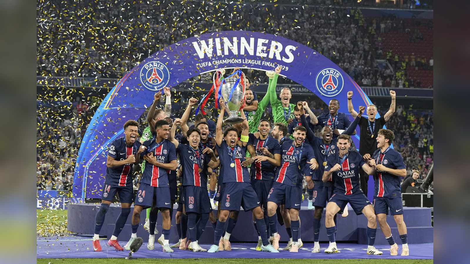 Paris Saint-Germain soccer players celebrating with a trophy under a winners arch