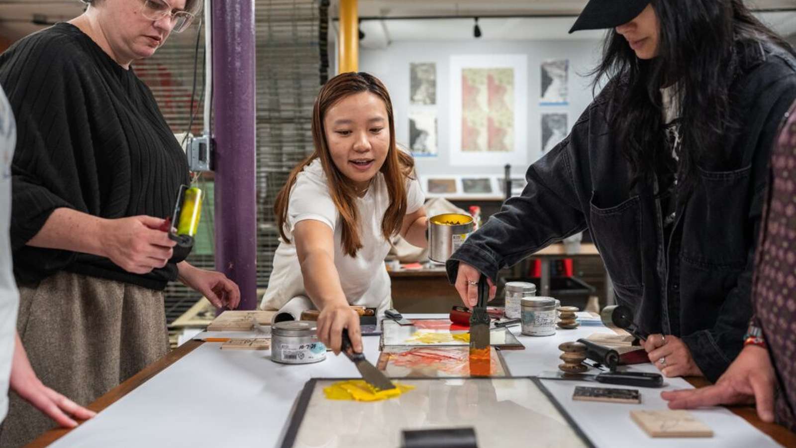 Several people gathered around a table engaged in a hands-on crafting and printmaking workshop