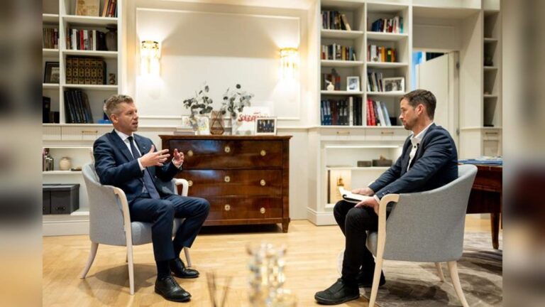 Hungarian politician Peter Magyar sitting in an armchair and speaking during an interview in an offi
