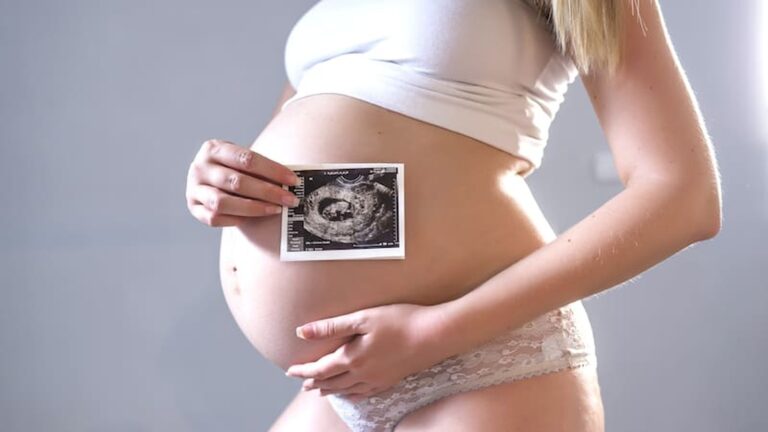 Pregnant woman holding an ultrasound scan against her belly