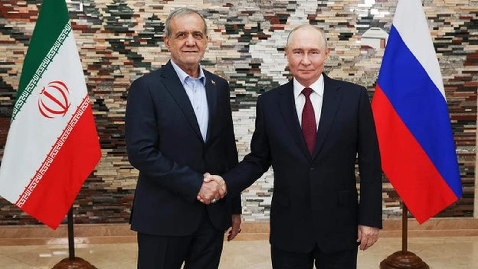 Russian President Vladimir Putin shaking hands with an Iranian official in front of national flags