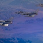 Three Royal Air Force Typhoon fighter jets flying in formation over a mountainous desert landscape