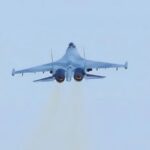 A Russian Su-35 fighter jet flying in the sky from a rear angle view