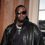 Sean Diddy Combs wearing dark sunglasses and a black leather jacket indoors