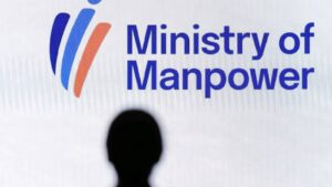 Silhouette of a person standing in front of the Ministry of Manpower sign in Singapore
