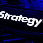 Close up of Strategy brand name and bitcoin symbol displayed on a dark surface with blue lighting