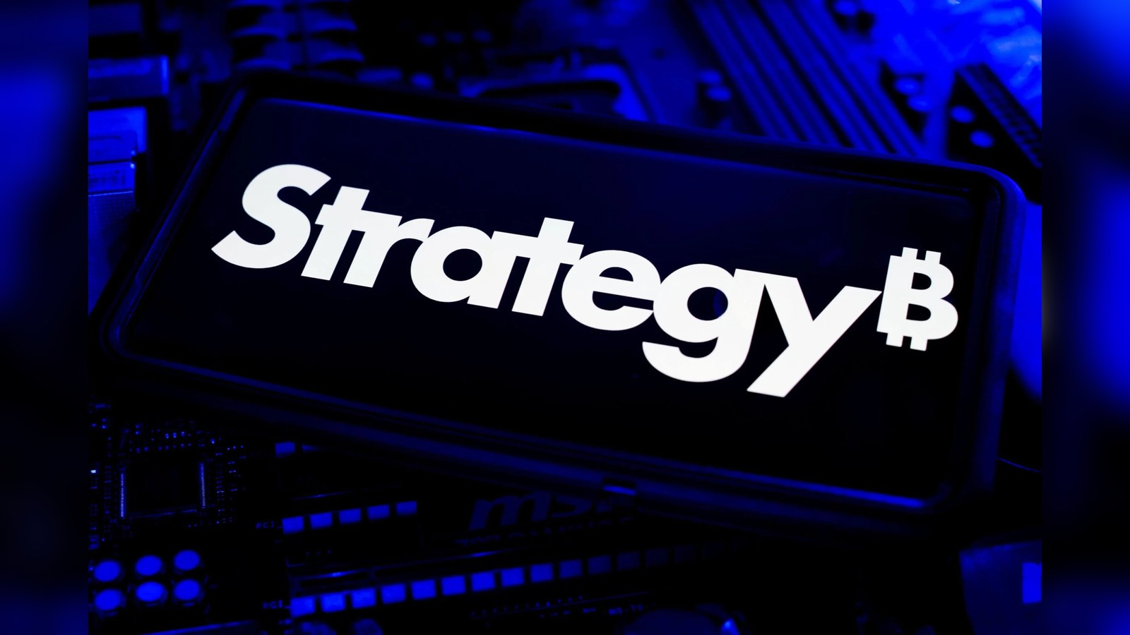 Close up of Strategy brand name and bitcoin symbol displayed on a dark surface with blue lighting