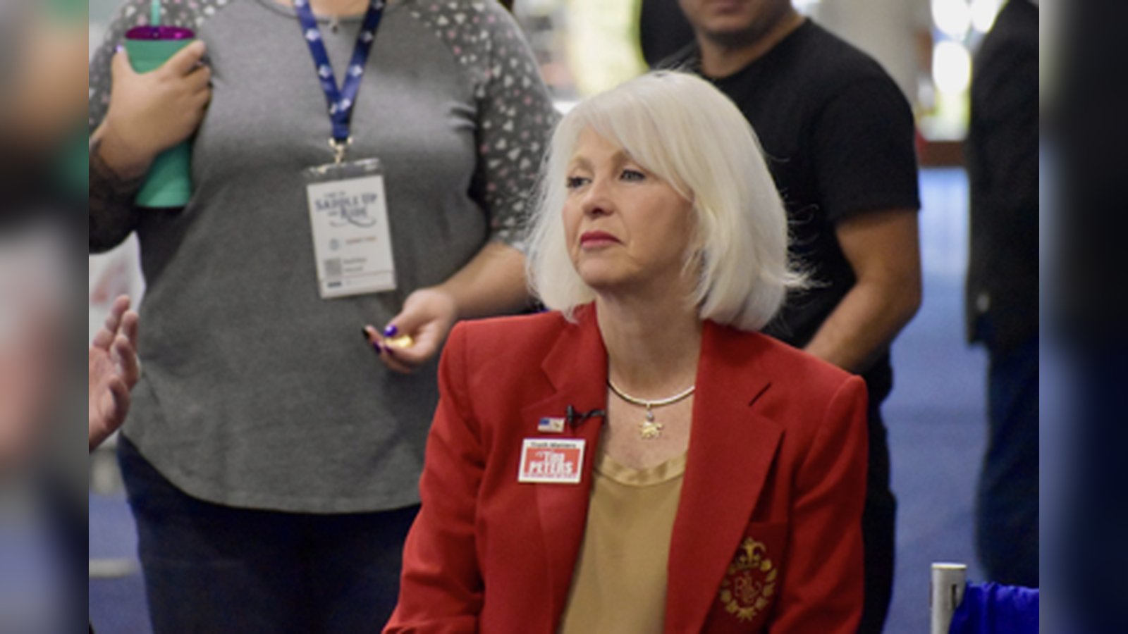 Tina Peters with white hair wearing a red blazer at a public event