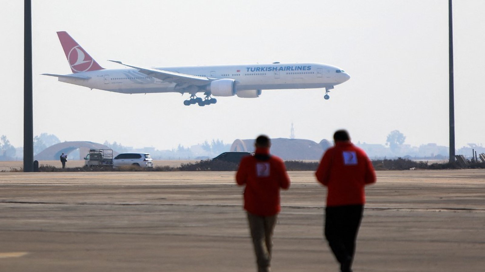 A Turkish Airlines passenger jet landing at an airport with ground crew in foreground