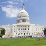 The United States Capitol building viewed from the National Mall under a blue sky