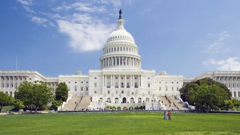 The United States Capitol building viewed from the National Mall under a blue sky