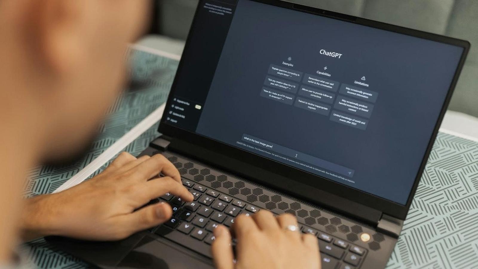 Close-up of a person typing on a laptop keyboard displaying the ChatGPT interface