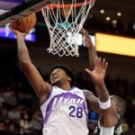 A Utah Jazz basketball player wearing number 28 goes up for a slam dunk during a game