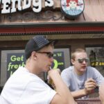 Young customers eating food at an outdoor table in front of a Wendys restaurant