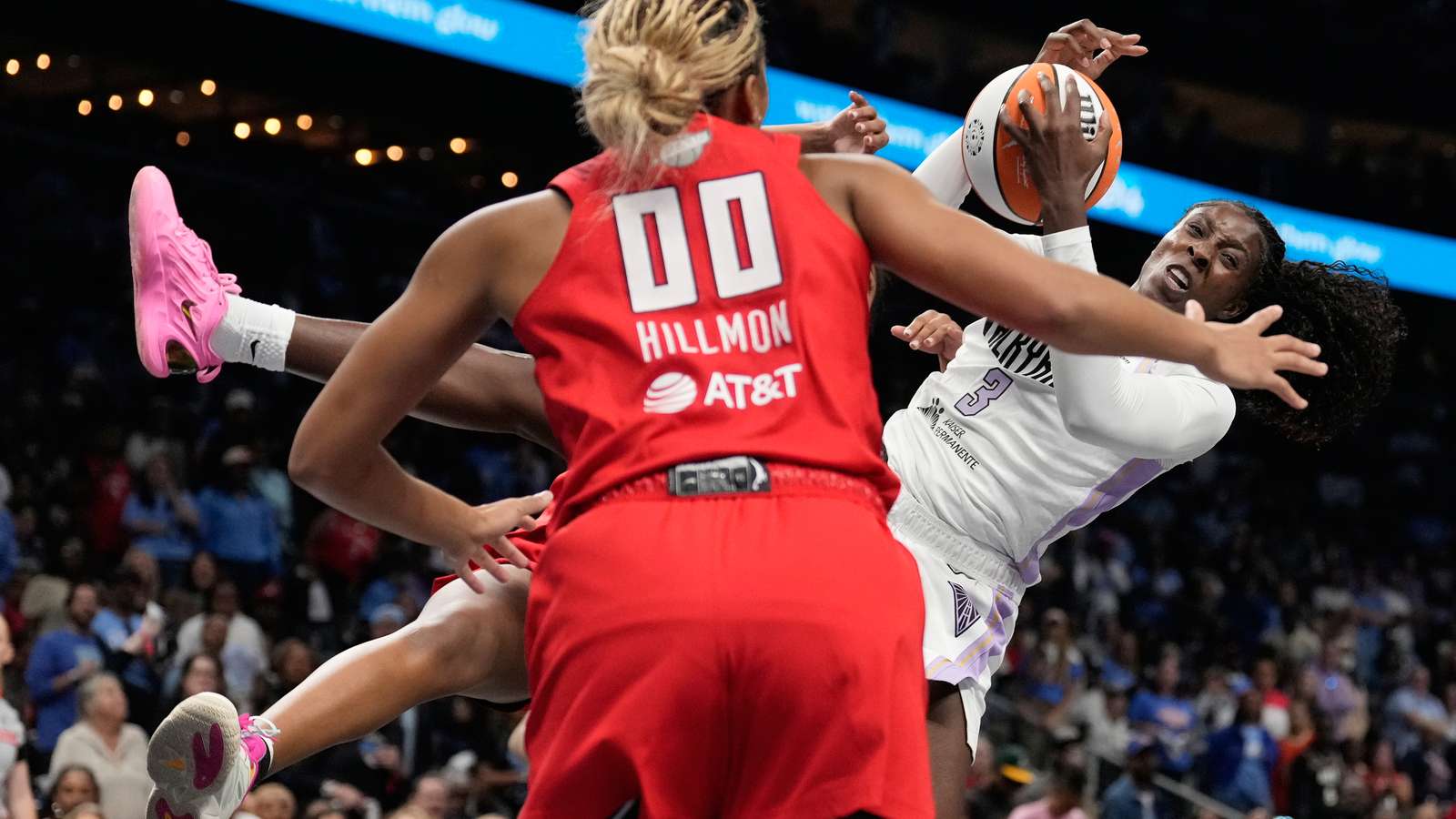 Two WNBA basketball players competing fiercely for the ball during a game